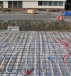 Installation of PEX tubing for radiant floor heating in a car repair shop.